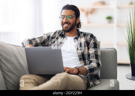 Glücklicher Freiberufler aus dem Nahen Osten, der seinen Online-Job genießt Stockfoto