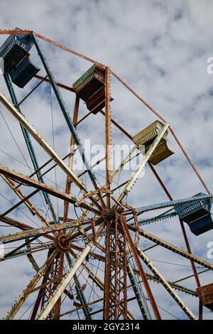 Blick aus der Wurmperspektive auf ein Riesenrad in einem verlassenen Freizeitpark Stockfoto