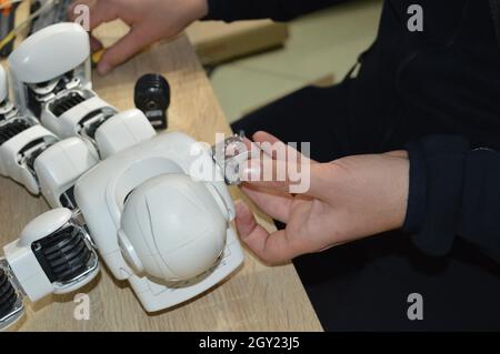 Mann repariert einen Roboter. Nahaufnahme von männlichen Händen, die einen zerbrochenen kleinen Roboter fixieren Stockfoto