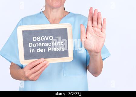 Krankenschwester in blauer Uniform mit einer Tafel mit der Aufschrift „DSGVO - Datenschutz in der Praxis“ Stockfoto