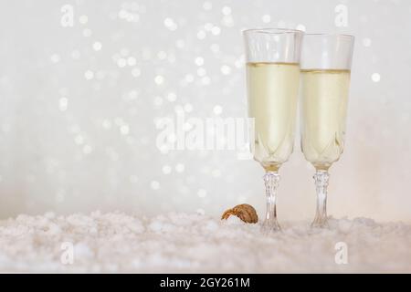 Zwei Sektgläser auf Schnee mit Bokeh-Hintergrund mit Kopierfläche Stockfoto