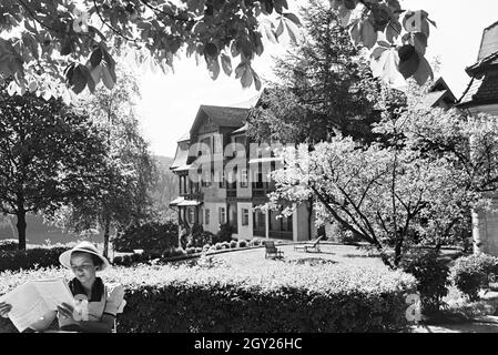 Eine junge Frau entspannt bei der Zeitschriftenlektüre im Garten, Freudenstadt, Deutschland 1930er Jahre. Eine junge Frau bei einem Magazin im Garten, Freudenstadt, Deutschland 1930. Stockfoto