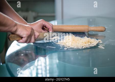 Eine unkenntliche Frau schneidet Nudeln. Frauenhände aus der Nähe. Stockfoto