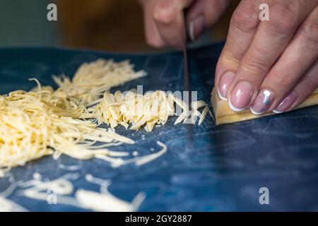 Eine unkenntliche Frau schneidet Nudeln. Frauenhände aus der Nähe. Stockfoto
