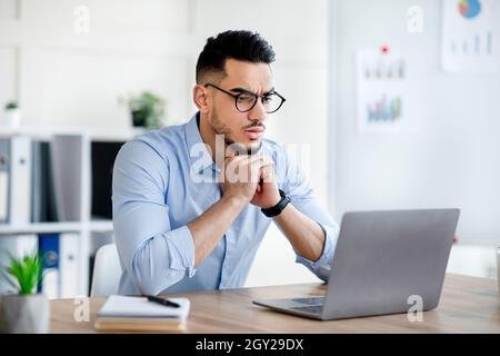 Gestresster arabischer Mann mit Laptop, Probleme bei der Ausführung von Arbeitsaufgaben, Fehler bei Geschäftsprojekt im Büro Stockfoto