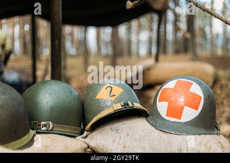 Metallhelme der United States Army Infantry Soldier im Zweiten Weltkrieg Helme In Der Nähe Camping Zelt In Forest Camp Stockfoto