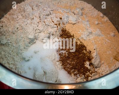 Roggenmehl, Salz, gemahlener Kreuzkümmel und getrocknete Hefe in einer Edelstahlschüssel - Basis für Brotteig - selektiver Fokus Stockfoto