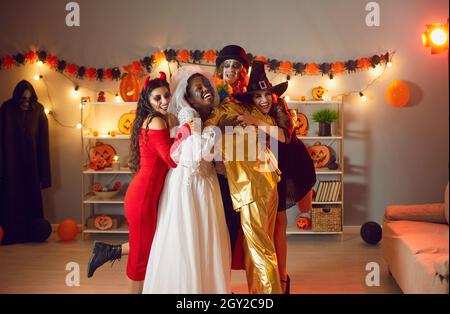Eine Gruppe glücklicher junger Menschen in gruseligen Kostümen umarmte sich auf der Halloween-Party Stockfoto