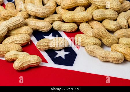 Erdnüsse in Schale auf der Flagge von Mississippi. Erdnussanbau, Handel, Zölle und Marktpreiskonzept Stockfoto