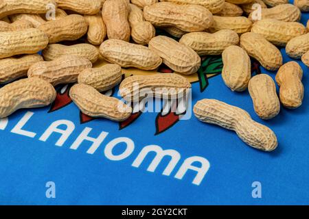 Erdnüsse in Schale auf Flagge von Oklahoma. Erdnussanbau, Handel, Zölle und Marktpreiskonzept. Stockfoto