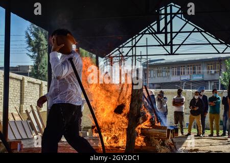 Srinagar, Indien. Oktober 2021. Ein Verwandter führt während seiner Verbrennung in Srinagar letzte Riten in der Nähe des brennenden Scheiterfeuers des ermordeten Makhan Lal Bindroo, eines hinduistischen pandit-Geschäftsmannes und Besitzers einer Apotheke, durch. Bindroo, ein kaschmirischer Hindu und zwei weitere Männer wurden am Dienstagabend bei separaten Angriffen von unbekannten Schützen getötet, die als Militante verdächtigt wurden. Kredit: SOPA Images Limited/Alamy Live Nachrichten Stockfoto