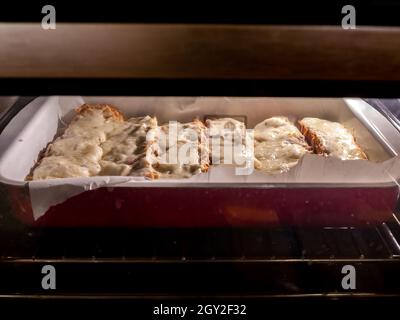 Blick auf Sandwiches im Ofen, während sie gegrillt werden und der Käse schmilzt. Stockfoto