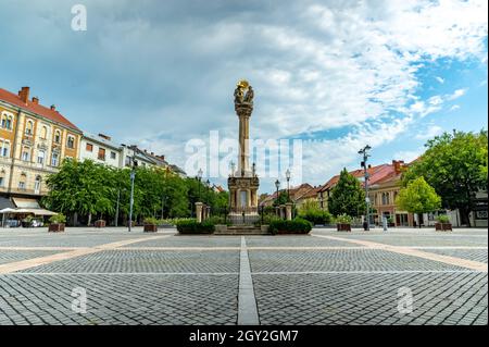 SZOMBATHELY, UNGARN - 15. AUGUST 2021: Blick auf die Statue der Heiligen Dreifaltigkeit oder die Szentharomsag szobor auf dem Hauptplatz oder Fo-Platz und die Menschen Stockfoto