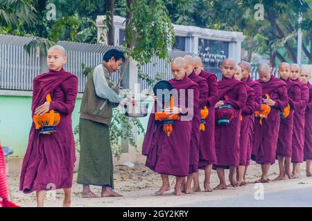 BAGAN, MYANMAR - 8. DEZEMBER 2016: Reihen buddhistischer Mönche mit Schalen, die ihre täglichen Almosen sammeln. Stockfoto