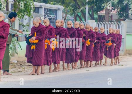 BAGAN, MYANMAR - 8. DEZEMBER 2016: Reihen buddhistischer Mönche mit Schalen, die ihre täglichen Almosen sammeln. Stockfoto