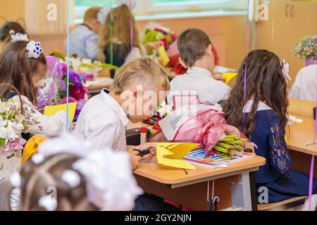 Erstklässler in der Lektion schneiden Zahlen für Anwendungen aus Papier aus. Schule, Wissenstag. Moskau, Russland, 1. September 2021 Stockfoto