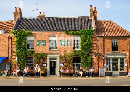 Die roten Backsteinfassaden von Bar & Restaurant No Twenty9 und Bakery No Thirty3 in Burnham Market, Norfolk, England. Stockfoto