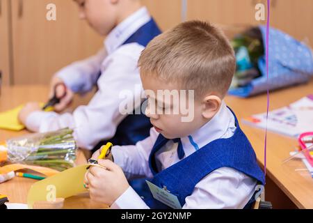 Erstklässler in der Lektion schneiden Zahlen für Anwendungen aus Papier aus. Schule, Wissenstag. Moskau, Russland, 1. September 2021 Stockfoto