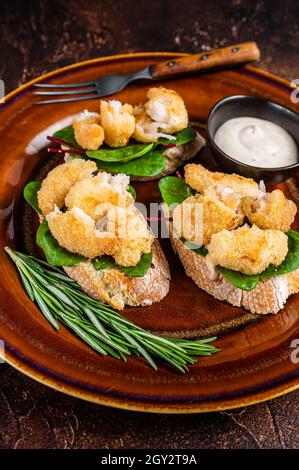 Sandwiches mit gebratenen Garnelen, Garnelen, Spinat und Mangold-Salat auf einem rustikalen Teller. Dunkler Hintergrund. Draufsicht Stockfoto
