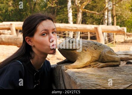 Ein junges Mädchen küsst einen Frosch, um ihn in einen hübschen Prinzen zu verwandeln Stockfoto