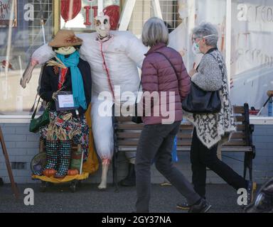 Richmond, Kanada. Oktober 2021. Am 6. Oktober 2021 laufen Menschen an einer Vogelscheuche vor einem Geschäft im Steveston Village in Richmond, British Columbia, Kanada, vorbei. Vogelscheuchen werden außerhalb von Geschäften im Steveston Village erstellt und platziert, wo die Leute ermutigt werden, für die besten Designs des Jahres für den Steveston Scarecrow Crawl-Wettbewerb zu stimmen. Quelle: Liang Sen/Xinhua/Alamy Live News Stockfoto