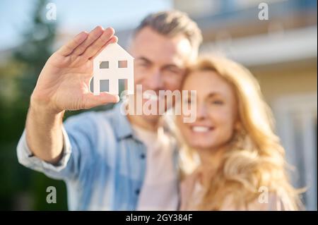 Hausschild in der Hand eines Mannes, der seine Frau umarmte Stockfoto