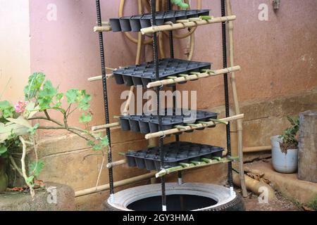 Ständer für Keimtablett oder Sämlingschale aus einem alten Reifen und Eisenstab, der im Garten des Hauses aufbewahrt wird Stockfoto
