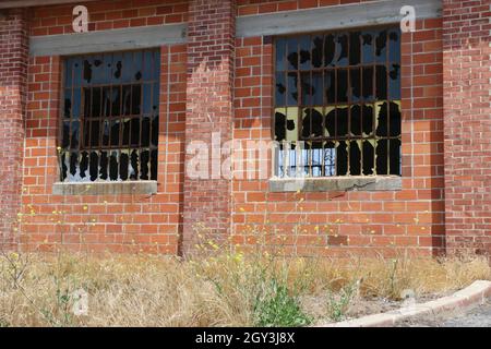 Verfallene, verlassene Backsteinlagerhalle mit zertrümmerten Fenstern. Stockfoto