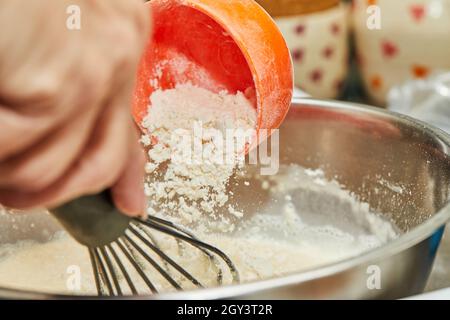 Den Teig in einer Schüssel kneten und Mehl dazugeben. Stockfoto