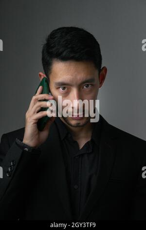 Porträt eines attraktiven ostasiatischen Geschäftsmannes, der am Telefon spricht Stockfoto