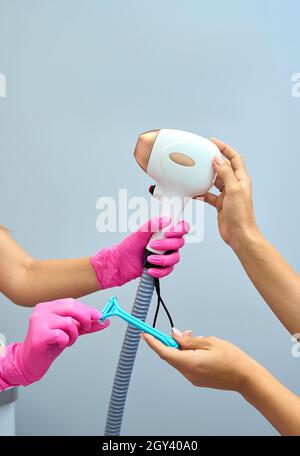 Eine Frau spielt eine Laser-Haarentfernungsmaschine. Sie hält einen funktionierenden Teil des Epilierers in ihren Händen und posiert für ein Foto. Es befindet sich in einem modernen Ba Stockfoto