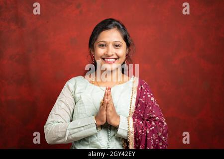 Glücklich lächelndes indisches Mädchen mit traditionellen ethnischen Kleid in namaste Geste Blick auf Kamera - Konzept der indischen Art der Begrüßung Stockfoto