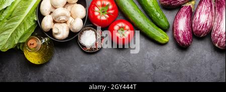 Zutaten zum Kochen auf dem Steintisch. Gemüse, Pilze, Gewürze und Salat. Draufsicht flach liegend Stockfoto