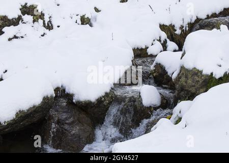 Flusswasser im Schnee in den Bergen Stockfoto