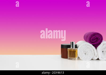 Stapel Handtücher, Flaschen mit Shampoo auf weißem Tisch Stockfoto