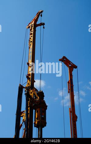 Die Türme von zwei Drehbohrgeräten stehen vor einem blauen Himmel. Stockfoto