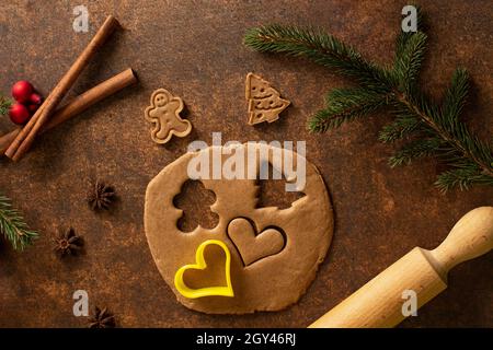 Lebkuchenteig, ausgerollt. Ein Lebkuchenmann, ein Weihnachtsbaum-Keks, ein Nudelholz, Zimtküllchen, Sternanisfrüchte, Weihnachtsbaumschmuck Stockfoto