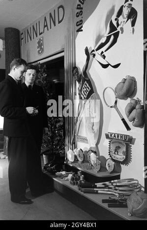 Zwei Besucher vor einem Ständer mit finnischen Sportartikeln auf der Leipziger Frühjahrsmesse, Deutschland 1941. Zwei Besucher vor einem stand der finnischen Sport waren auf der Leipziger Frühjahrsmesse, Deutschland 1941. Stockfoto