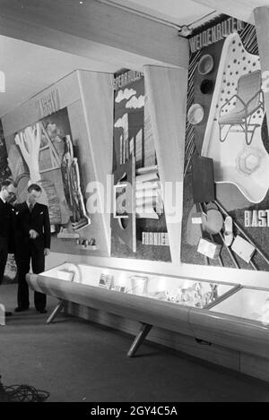 Angestellte der Leipziger Frühjahrsmesse vor einer Wand mit dem Baustoff Holz und einem Schaukasten"; Deutschland 1941. Mitarbeiter der Leipziger Frühjahrsmesse vor einer Wand mit der Baustoff Holz und die Vitrine; Deutschland 1941. Stockfoto