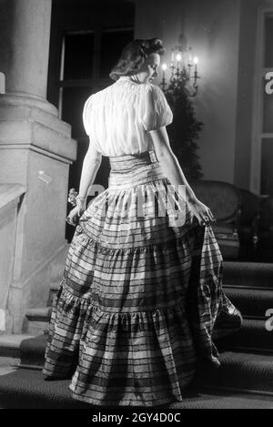 Ein Model bei der Präsentation eines folkloristischen Kleids, anlässlich der Wiener Modewoche im Haus der Mode ' Palais Lobkowitz', Deutschland 1940er Jahre. Ein Modell präsentiert ein folkloristisches Kleid, anlässlich der Wiener Modewoche im Haus der Mode ' Palais Lobkowitz', Deutschland 1940er Jahre. Stockfoto