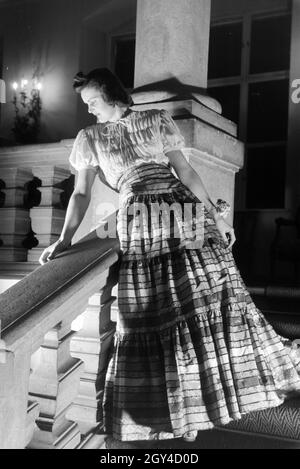 Ein Model bei der Präsentation eines folkloristischen Kleids, anlässlich der Wiener Modewoche im Haus der Mode ' Palais Lobkowitz', Deutschland 1940er Jahre. Ein Modell präsentiert ein folkloristisches Kleid, anlässlich der Wiener Modewoche im Haus der Mode ' Palais Lobkowitz', Deutschland 1940er Jahre. Stockfoto