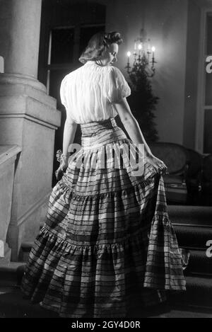 Ein Model bei der Präsentation eines folkloristischen Kleids, anlässlich der Wiener Modewoche im Haus der Mode ' Palais Lobkowitz', Deutschland 1940er Jahre. Ein Modell präsentiert ein folkloristisches Kleid, anlässlich der Wiener Modewoche im Haus der Mode ' Palais Lobkowitz', Deutschland 1940er Jahre. Stockfoto