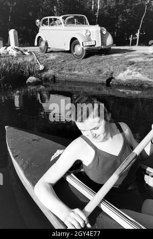 Junge Frau paddelt in einem Boot mit dem Siehe nahe des Ufers, Deutschland 1930er. Junge Frau Paddeln in einem Boot auf einem See in der Nähe des Flusses, Deutschland 1930. Stockfoto