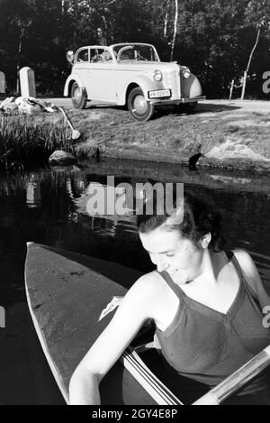 Junge Frau paddelt in einem Boot mit dem Siehe nahe des Ufers, Deutschland 1930er. Junge Frau Paddeln in einem Boot auf einem See in der Nähe des Flusses, Deutschland 1930. Stockfoto