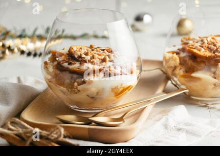 Weihnachtsdessert in Gläsern aus gebackenem Apfel, knusprigen Mandelplätzchen, Pudding, Marmelade, Joghurt, Zimt und geröstete Mandeln. Parfait Stockfoto