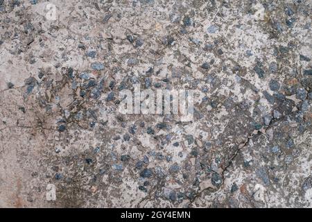 Zementboden mit kleinen Steinen. Schmutzig rissige alte graue Betonhintergrund Wand oder Boden mit poliertem Zement. Terrazzo-Struktur. Nahaufnahme. In Innenräumen. Stockfoto