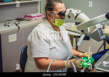Zahnärztliche Behandlung mit einem Mikroskop. Mann, der Zähne bei Zahnärzten untersucht hat. Termin beim Zahnarzt. Lifestyle, echtes Leben Stockfoto
