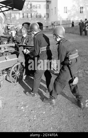 Eine Gruppe von der Kinderfeuerwehr mit dem Löschwagen bei einer Feuerwehrübung, Deutschland 1930er Jahre. Eine Gruppe von Junior Feuerwehrmänner ist die Vorbereitung der firewagon während ein Feuerwehrmann, Deutschland 1930. Stockfoto