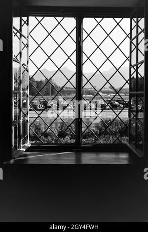 Blick aus einem Fenster auf einen Parkplatz vor dem Panorama der Chiemgau Alpen, Deutschland 1930er Jahre. Blick aus einem Fenster auf einen Parkplatz vor dem Panorama-Blick auf die Chiemgauer alpen, Deutschland 1930er Jahre. Stockfoto