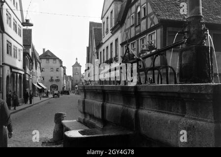 Eine von Fachwerkhäusern gesäumte Straße mit einem Springbrunnen in Rothenburg o.d. Tauber, Deutschland 1930er Jahre. Eine Straße mit Fachwerkhäusern und einem Brunnen in Rothenburg o.d. Tauber, Deutschland 1930 gesäumt. Stockfoto